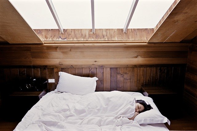 Žena spí v posteli v podkrovnej spálni